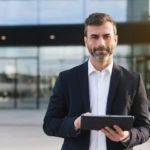 a man in a suit is holding a tablet