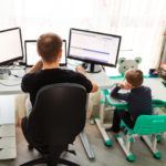 two children sitting at desks in front of computer monitors