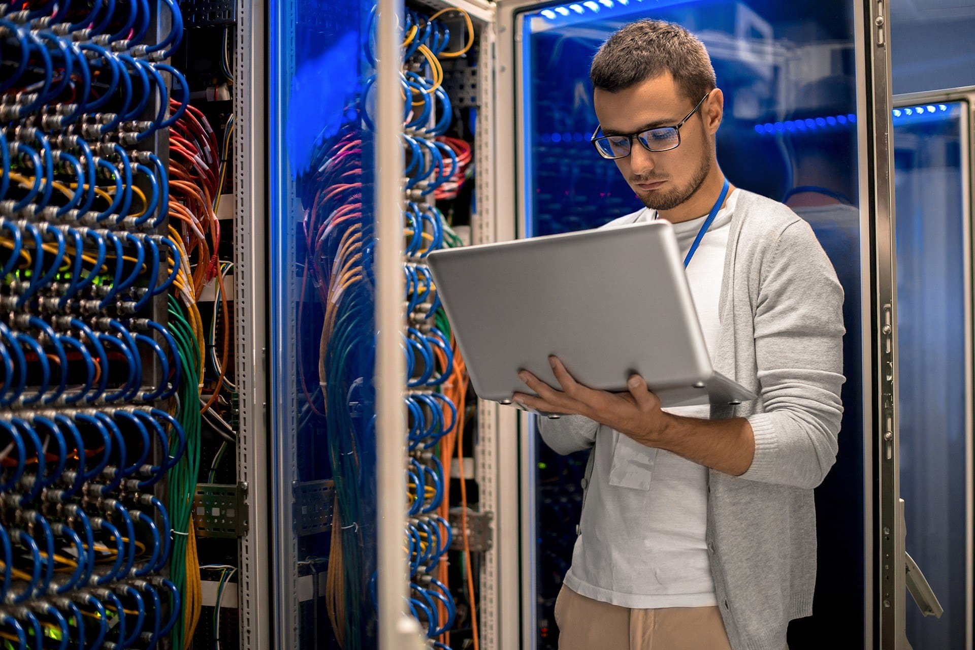 a man standing in front of a server holding a laptop