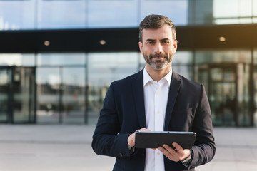 a man in a suit is holding a tablet