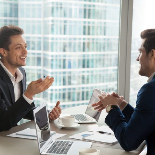 two men sitting at a table talking to each other