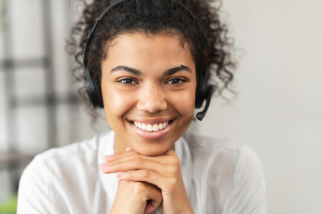 a woman wearing a headset smiles at the camera